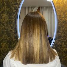 Capelli lisci castano chiaro con schiariture bionde visti da dietro davanti a specchio ovale illuminato e carta da parati damascata